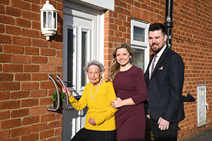 Housing associations staff outside front door of improved home solutions