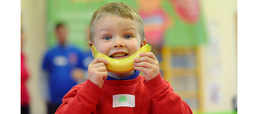 Boy eats banana as white goods and breakfasts provided to disadvantaged families